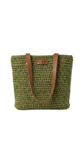 Green woven handbag with brown leather straps on a white background